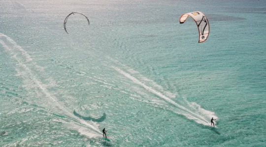 Kitesurfeur naviguant dans la lagune turquoise avec ailes colorées